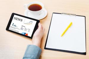 tablet PC with business news on screen at table photo