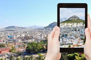 turista tomando fotos del paisaje urbano de atenas