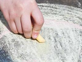 girl drawing with colored crayons on pavement photo