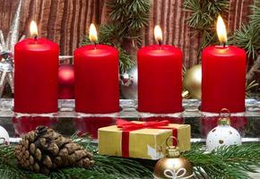 Red Christmas candles and Christmas gift boxes against wooden background photo