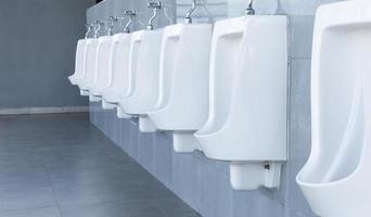 Men's room with white porcelain urinals in line in gas station photo