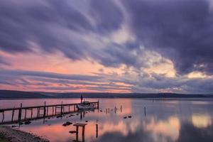 emocionante puesta de sol en un lago con puente y barco. foto