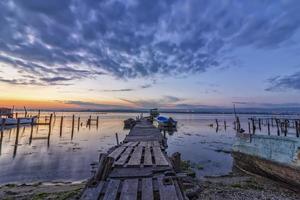 emocionante paisaje de larga exposición en un lago con muelle de madera y barcos foto