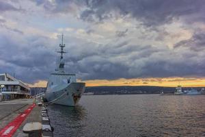 Military navy ship in port. Military sea landscape with cloudy sky at sunset photo