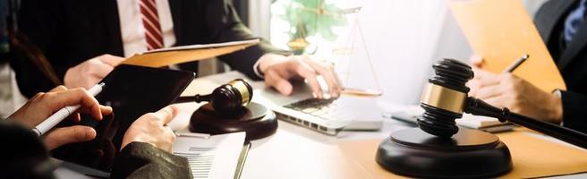 Business and lawyers discussing contract papers with brass scale on desk in office. Law, legal services, advice, justice and law concept picture with film grain effect photo