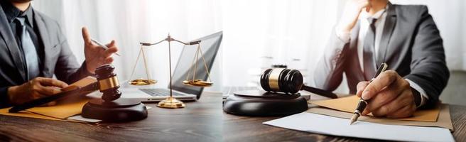 Justice and law concept.Male judge in a courtroom with the gavel, working with, computer and docking keyboard, eyeglasses, on table in morning light photo