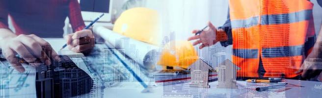 Two colleagues discussing data working and tablet, laptop with on on architectural project at construction site at desk in office photo