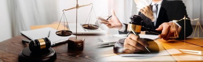 Justice and law concept.Male judge in a courtroom with the gavel, working with, computer and docking keyboard, eyeglasses, on table in morning light photo