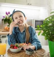 Cute little girl eats fruit salad photo