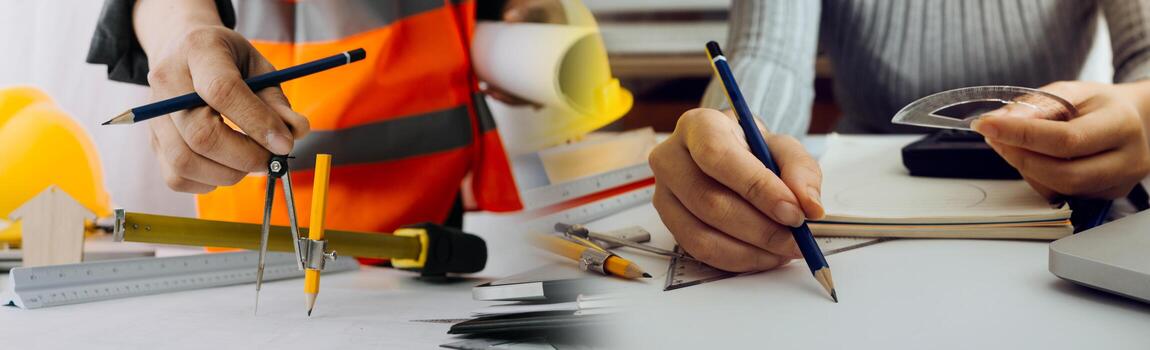 Two colleagues discussing data working and tablet, laptop with on on architectural project at construction site at desk in office photo