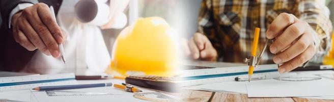 Two colleagues discussing data working and tablet, laptop with on on architectural project at construction site at desk in office photo