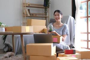 Startup small business entrepreneur SME, asian woman packing cloth in box. Portrait young Asian small business owner home office, online sell marketing delivery, SME e-commerce telemarketing concept photo