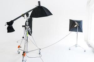 Empty photo studio with lighting equipment. Photographer workplace interior with professional tool set gear. Flash light white background scenes ready for studio shooting. Modern photographer studio