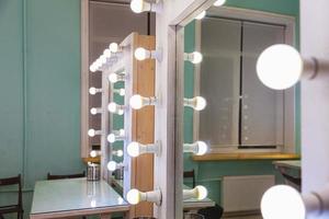 lugar de maquillaje de mujer vacío con espejo y bombillas. maquillador en el lugar de trabajo en la sala de maquillaje moderna. interior de barbería. vestidor con espejo de maquillaje y mesa. diseño de interiores de estilo clásico moderno. foto