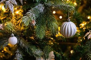 Classic Christmas decorated New year tree. Christmas tree with white and silver decorations, ornaments toy and ball. Modern classical style interior design apartment. Christmas eve at home. photo