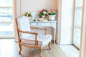 Beautiful luxury classic white bright clean interior bedroom in baroque style with large window, armchair and flower composition. photo