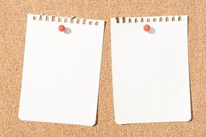 dos hojas de papel de cuaderno en blanco fijadas en el tablero de corcho. maqueta de plantilla foto