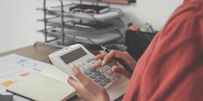 mujer de negocios que usa calculadora y computadora portátil para hacer finanzas matemáticas en un escritorio de madera en la oficina y el fondo de trabajo comercial, impuestos, contabilidad, estadísticas y concepto de investigación analítica foto