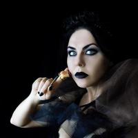 dark hair gothic woman with black lips make up and dry rose in her hand photo