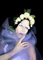 retrato conceptual de mujer extraña en corona de rosas blancas con maquillaje de fantasía para da de muertos foto