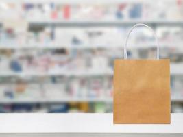 Paper bag on Pharmacy drugstore counter table with medicine and healthcare product on shelves blur background photo