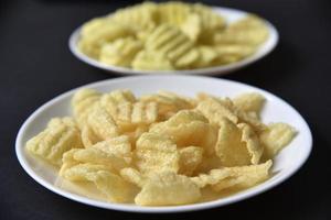 deliciosos chips de maíz con pimienta en un plato blanco. aperitivo de cerveza en un plato sobre un fondo negro. foto