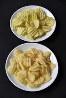 Delicious peppery corn chips on a white plate. Beer appetizer on a plate on a black background. photo