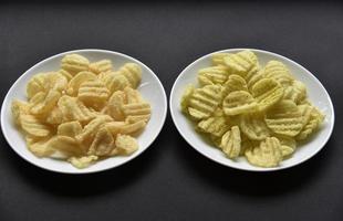 Delicious peppery corn chips on a white plate. Beer appetizer on a plate on a black background. photo