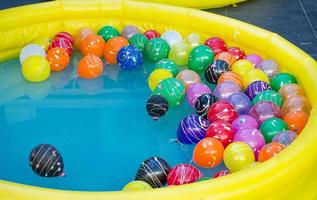 piscina de goma amarilla con bolas de colores en el agua. foto