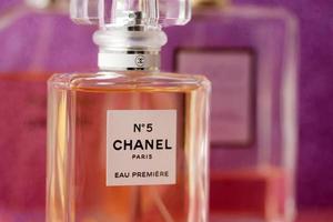 TERNOPIL, UKRAINE - SEPTEMBER 2, 2022 Chanel Number 5 Eau Premiere worldwide famous french perfume bottle among other perfumes on shiny glitter background in purple colors photo