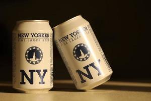 TERNOPIL, UKRAINE - JULY 18, 2022 Two cans of New Yorker fine lager beer with original logo and design on brown retro background photo