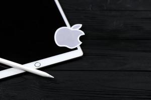 KHARKIV, UKRAINE - JANUARY 27, 2021 Brand new Apple iPad and Apple Pencil and gray company logo on black background. Apple Inc. is an American technology company photo