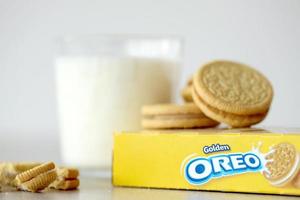 TERNOPIL, UKRAINE - MAY 28, 2022 Oreo golden crispy cookies with glass of milk on white background. The brand Oreo is owned by company Mondelez international photo