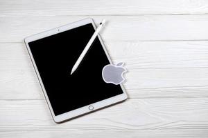 KHARKIV, UKRAINE - JANUARY 27, 2021 Brand new Apple iPad and Apple Pencil and gray company logo on white background. Apple Inc. is an American technology company photo