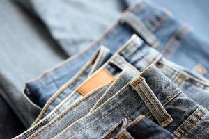 Many jeans in stack in wardrobe room. Row of pants denim jeans in closet. Concept of buy, sell, shopping and fashionable clothes photo