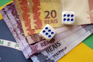 cubos de dados con billetes de dinero brasileño en la bandera de la república de brasil. concepto de suerte y juego en brasil foto