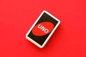 TERNOPIL, UKRAINE - MAY 15, 2022 Many colorful UNO game cards on red background. UNO is an American shedding-type card game that is played with a specially printed deck photo