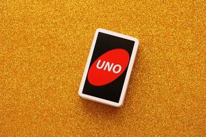 TERNOPIL, UKRAINE - MAY 15, 2022 Many colorful UNO game cards on golden background. UNO is an American shedding-type card game that is played with a specially printed deck photo