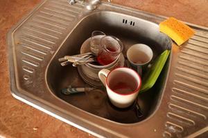 Stack of dirty dishes with food leftovers in the kitchen sink. Unwashed dishes photo