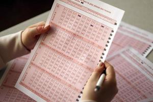 llenando un boleto de lotería. una joven juega a la lotería y sueña con ganar el premio mayor foto