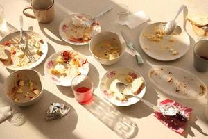 platos sucios vacíos con cucharas y tenedores en la mesa después de la comida. concepto de final de banquete. platos sin lavar foto