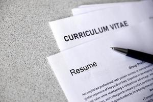 Top view of stack of office documents including resume and cv forms on the desk close to pen. Job seeking process. Hunting for workplace photo