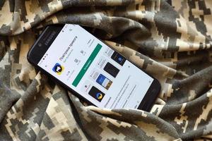 ternopil, ucrania - 24 de abril de 2022 aplicación de sirena de ataque aéreo para teléfono móvil en la pantalla del teléfono inteligente en el camuflaje militar foto
