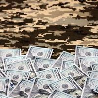 US dollar bills on fabric with texture of Ukrainian military pixeled camouflage. Cloth with camo pattern in grey, brown and green pixel shapes photo