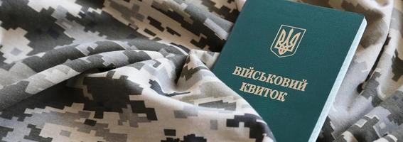 Ukrainian military ID on fabric with texture of pixeled camouflage. Cloth with camo pattern in grey, brown and green pixel shapes with Ukrainian army personal token photo