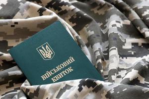 Ukrainian military ID on fabric with texture of pixeled camouflage. Cloth with camo pattern in grey, brown and green pixel shapes with Ukrainian army personal token photo