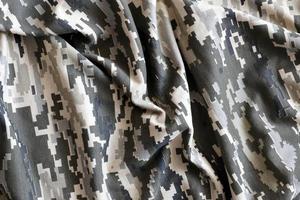 Fabric with texture of Ukrainian military pixeled camouflage. Cloth with camo pattern in grey, brown and green pixel shapes. Official uniform of Ukrainian soldiers photo