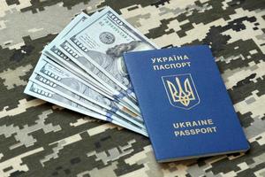 Ukrainian foreign passport on fabric with texture of military pixeled camouflage. Cloth with camo pattern in grey, brown and green pixel shapes and Ukrainian ID photo