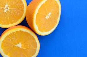 Top view of a several orange fruit slices on bright background in blue color. A saturated citrus texture image photo