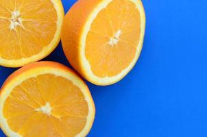 vista superior de varias rodajas de fruta naranja sobre fondo brillante en color azul. una imagen de textura cítrica saturada foto